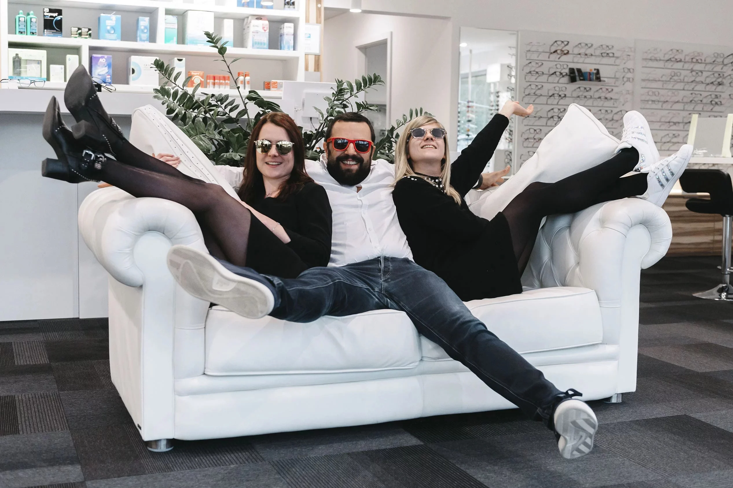 L'équipe du magasin pose avec des lunettes de soleil sur un canapé blanc