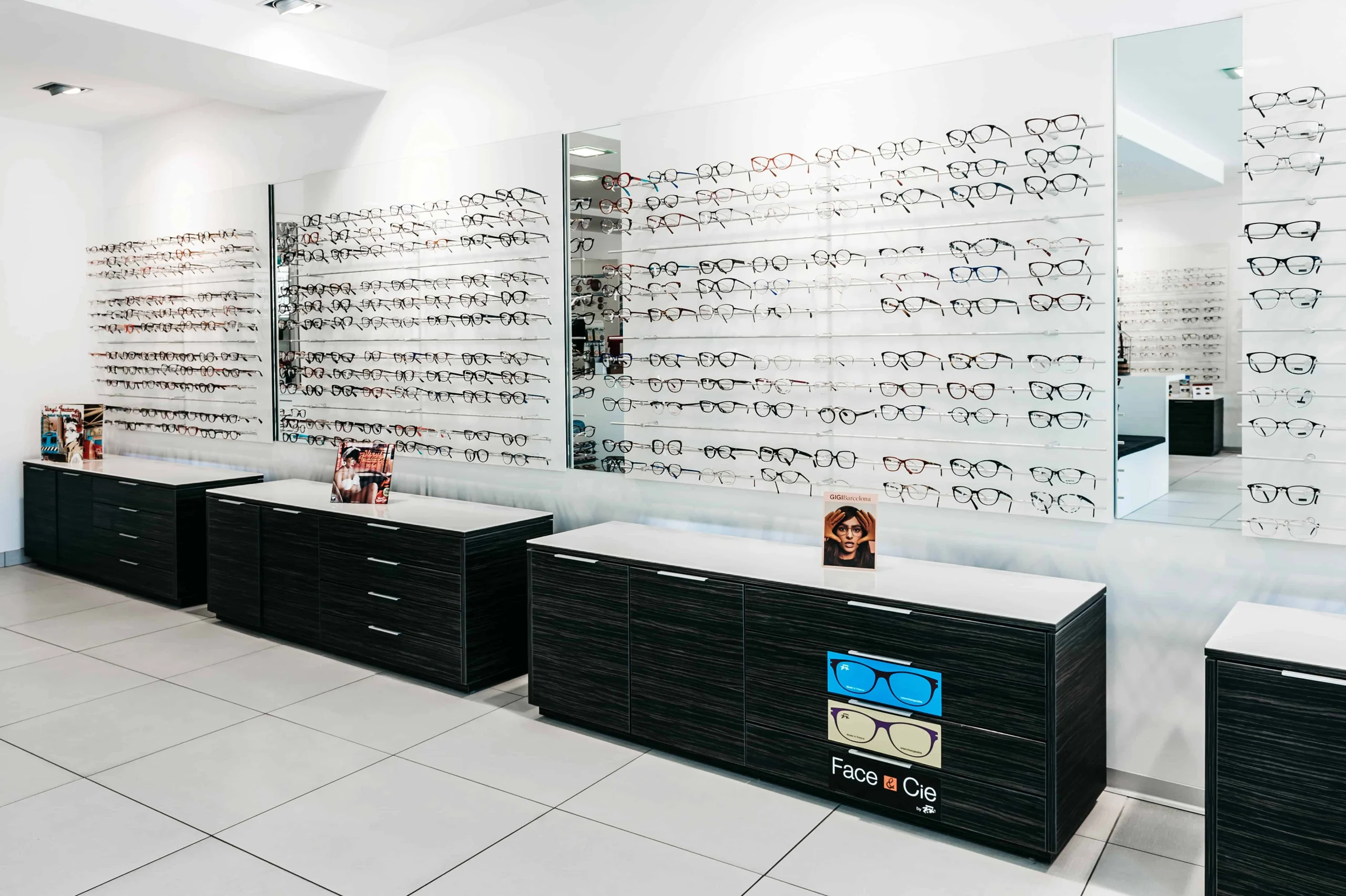 L'intérieur du magasin avec ses présentoirs à lunettes de vue, ses commodes en bois noires et ses miroirs muraux