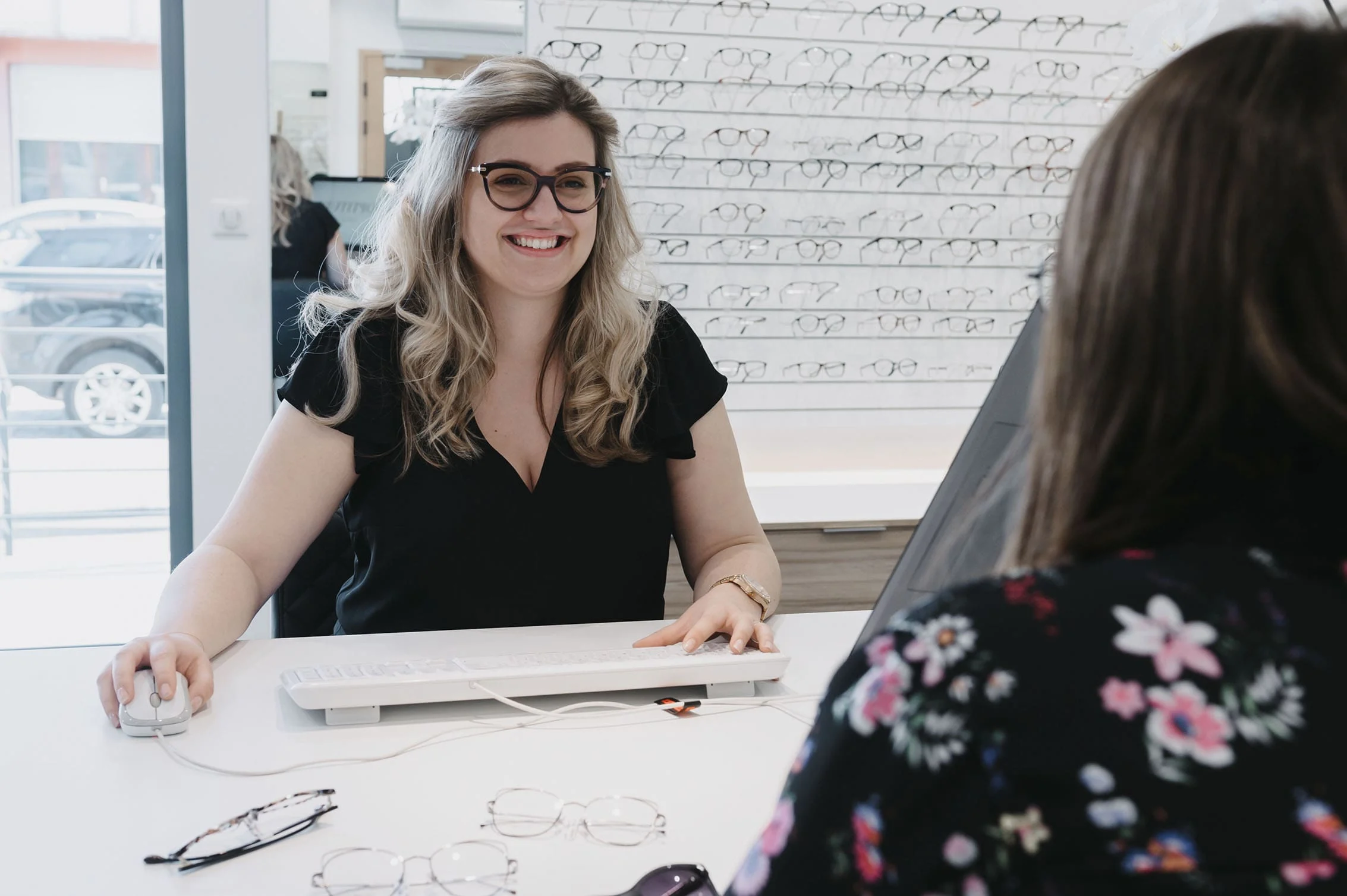 MN_OptitudeAltkirch_039 Une opticienne discute avec une cliente, elles sont assises autour d'un bureau sur lequel sont posées des lunettes de vue