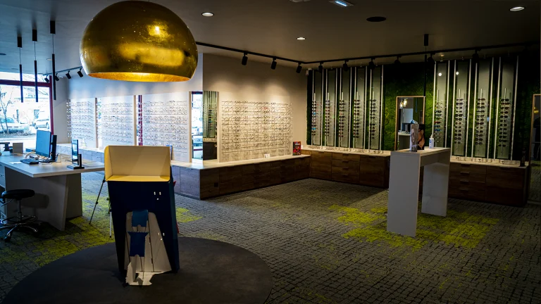 Intérieur du magasin avec ses présentoirs à lunettes et son abat jour en métal doré